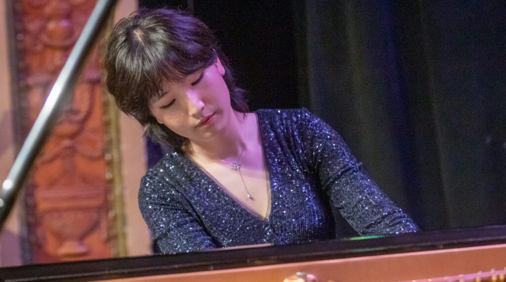 Woman in black gown plays piano at Young Texas Artists Music Competition