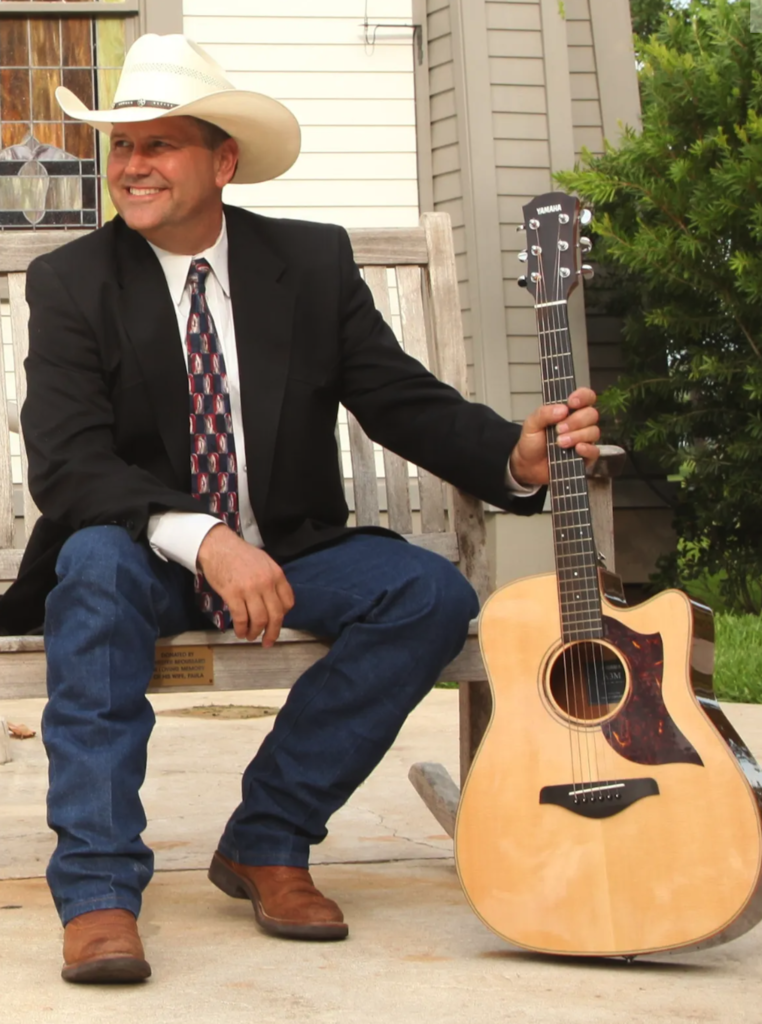 Man in cowboy hat sitting with guitar
